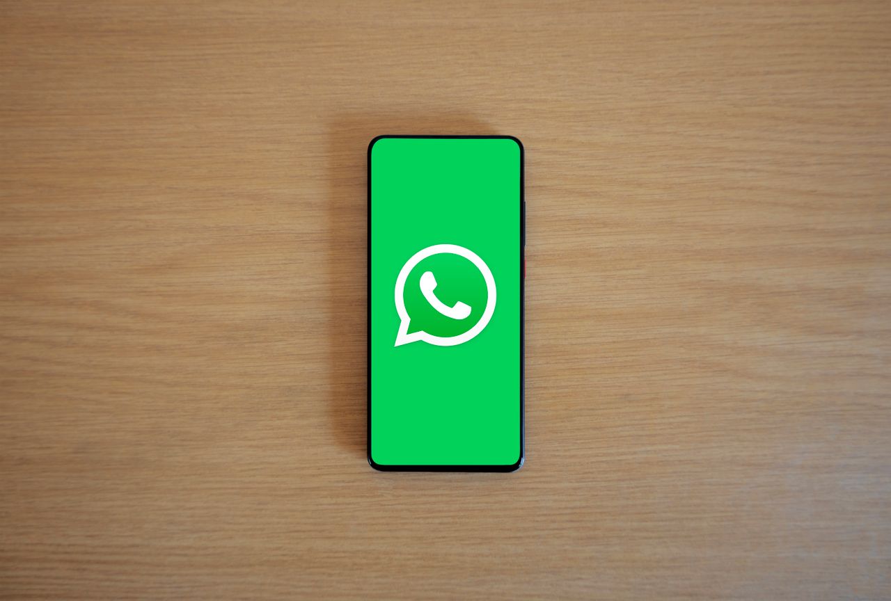 Crafting Captivating Headlines: Your awesome post title goes here Top view of smartphone displaying WhatsApp logo on a wooden background, representing technology and communication.
